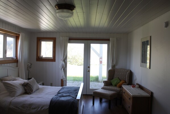 A bedroom with a bed, a chair, a dresser, and a window.