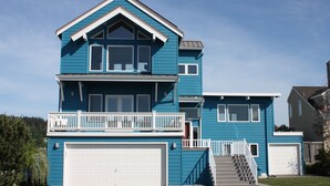 Ein zweistöckiges Haus mit weißer Garagentür, einem Balkon mit weißen Geländern und einer Treppe, die zum zweiten Stock führt.