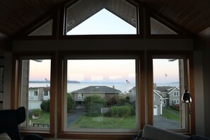 A room with a large window overlooking a residential area and a body of water.