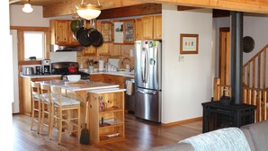 Eine geräumige Küche mit Holzschränken, einem Edelstahlkühlschrank und einem Kaminofen.