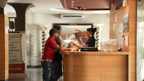 A reception area with a wooden counter, a decorative column, and a sign on the wall. - Hotel Ampuria Inn (Castello d'Empuries)