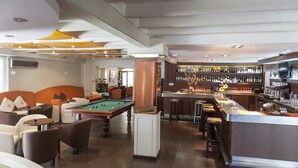 A modern lounge area with a pool table, comfortable seating, and a bar with a variety of liquor bottles. - Hotel Ampuria Inn (Castello d'Empuries)