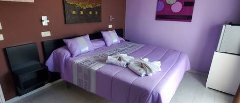 Un dormitorio con cama, un reloj de pared y un refrigerador.