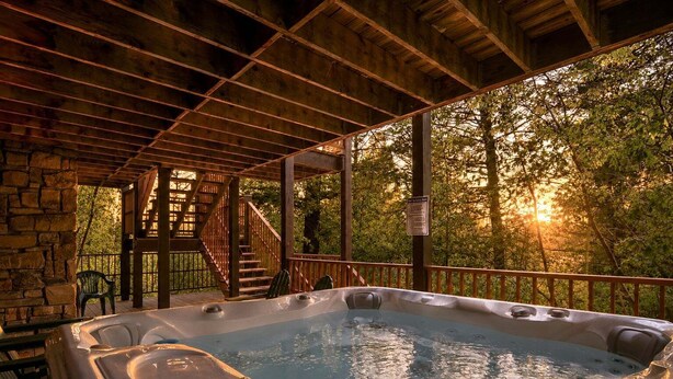 A hot tub in a covered outdoor area with a wooden deck and stone walls. - RMR: The Village House in Teton Village (Teton Village)