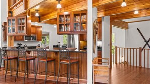 A spacious kitchen with wooden cabinets, a central island with bar stools, and a staircase leading to an upper level. - RMR: The Village House in Teton Village (Teton Village)