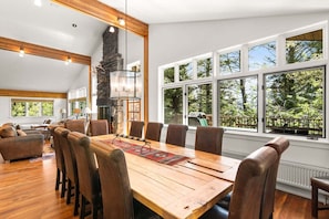 A spacious dining area with a large wooden table, leather chairs, and a stone fireplace. - RMR: The Village House in Teton Village (Teton Village)