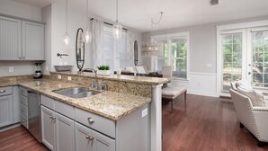 Una cocina con encimeras de granito, un lavamanos doble y una zona de comedor con banco y mesa.