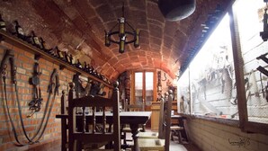 Une cave rustique aux murs de briques, meublée de meubles en bois et dotée d’un luminaire suspendu.