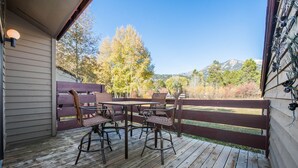 Une terrasse en bois avec une table et des chaises, une clôture en bois et une vue sur les arbres et les montagnes.
