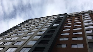 A tall, multi-story building with a modern architectural design, featuring a mix of brick and glass facade, and numerous windows. - Central Santiago (Santiago)