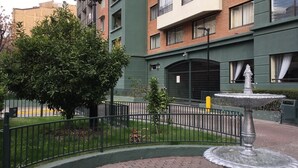 A courtyard with a fountain, a tree, and a building with multiple windows and balconies. - Central Santiago (Santiago)