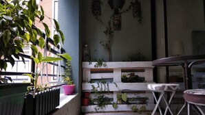 A small balcony with potted plants, a metal table, and a white railing. - Central Santiago (Santiago)