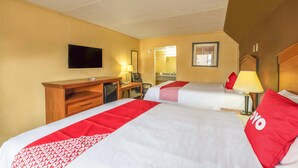 Een hotelkamer met twee bedden, een bureau, een televisie en een spiegel.