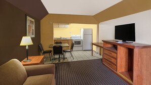 Een compacte hotelkamer met kitchenette, een flatscreen televisie, een bank en een kamerkleed met dessin.