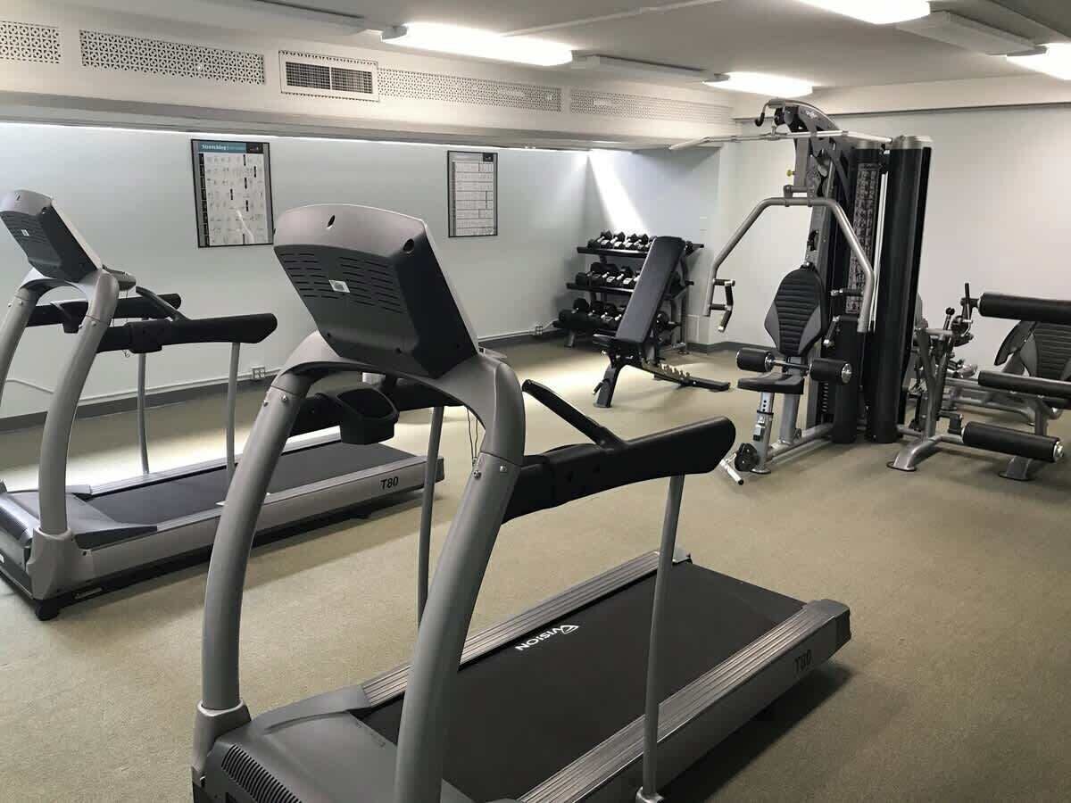 A gym with treadmills, weight machines, and dumbbells.