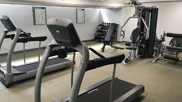 A gym with treadmills, weight machines, and dumbbells.