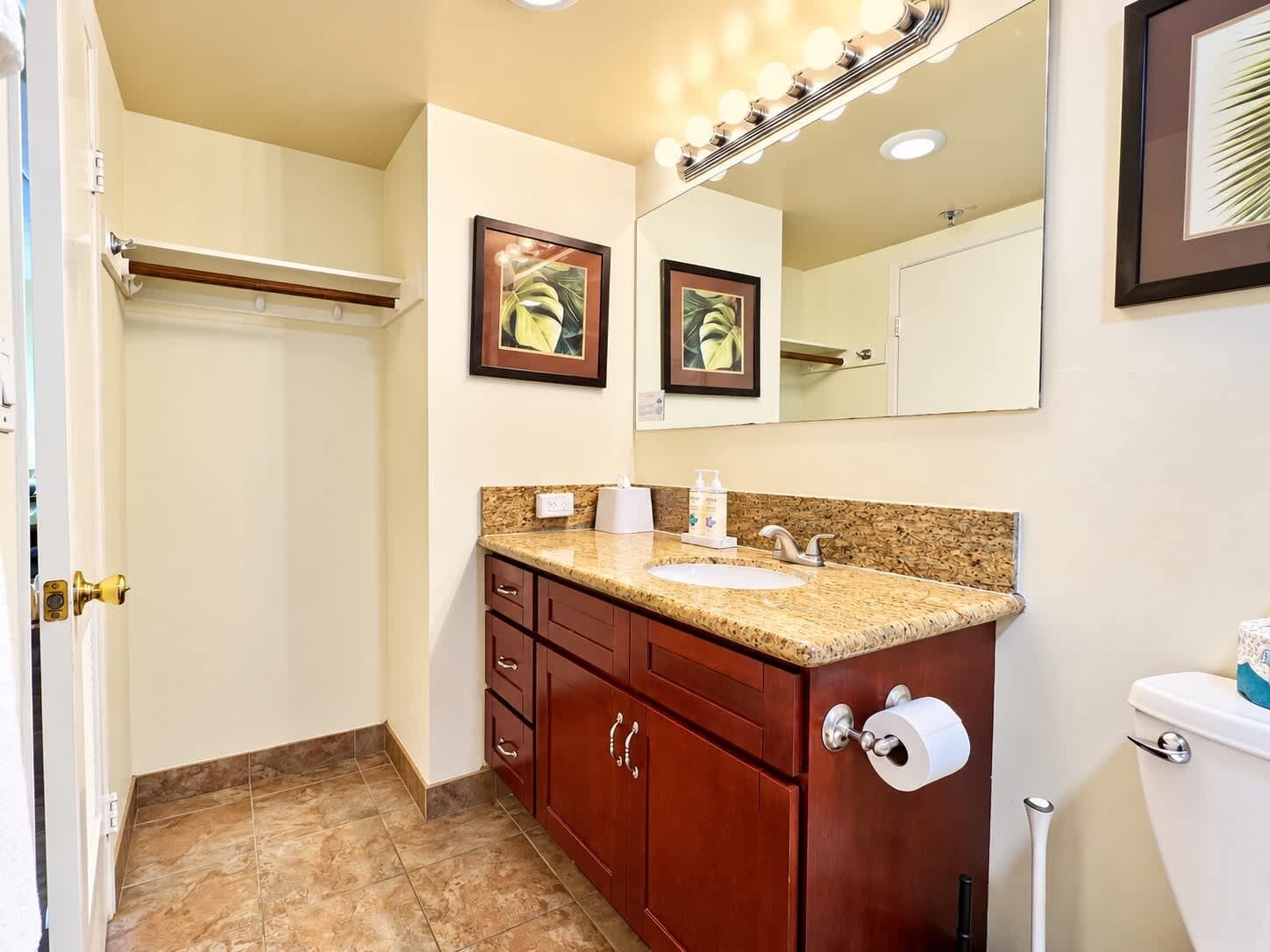 A bathroom with a vanity, sink, mirror, and toilet.