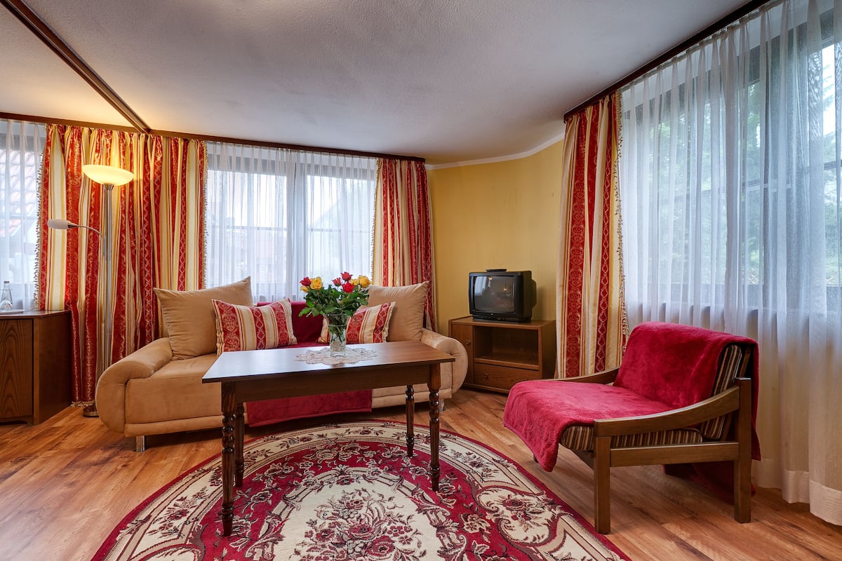 Ein Wohnzimmer mit Sofa, Sessel, Couchtisch und Fernseher.