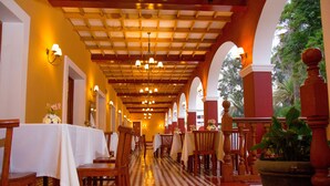 A corridor with tables and chairs, wooden ceiling, and a checkered floor. - DM Hoteles Mossone Ica (Ica)