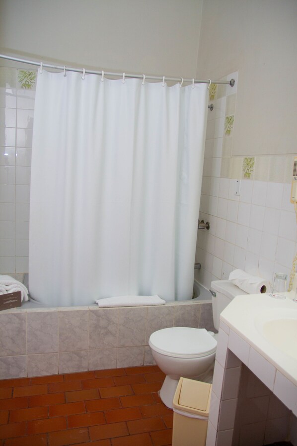 Un baño con cortina de ducha, inodoro y lavamanos.