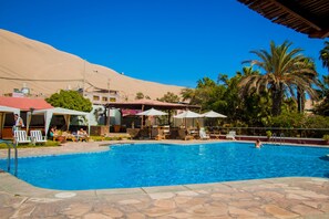 Una piscina al aire libre, sombrillas