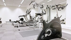 Ein Fitnessstudio mit Cardiogeräten, Kraftmaschinen und einer Spiegelwand.