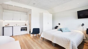 Ein modernes Schlafzimmer mit einem großen Bett, einem Schreibtisch und einer Küchenzeile.