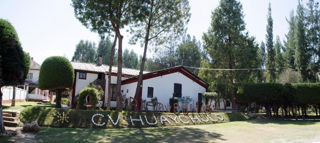 A building with a white facade and red trim, surrounded by trees and a well-maintained lawn.