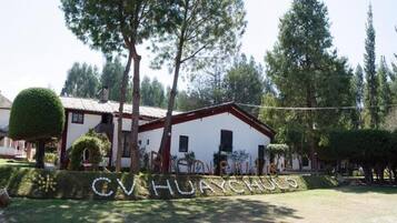 A building with a white facade and red trim, surrounded by trees and a well-maintained lawn.