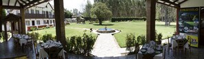 A courtyard with a fountain, dining tables set for a meal, and a view of the surrounding area including a building and trees. - Centro Vacacional Huaychulo (Nueve de Julio)