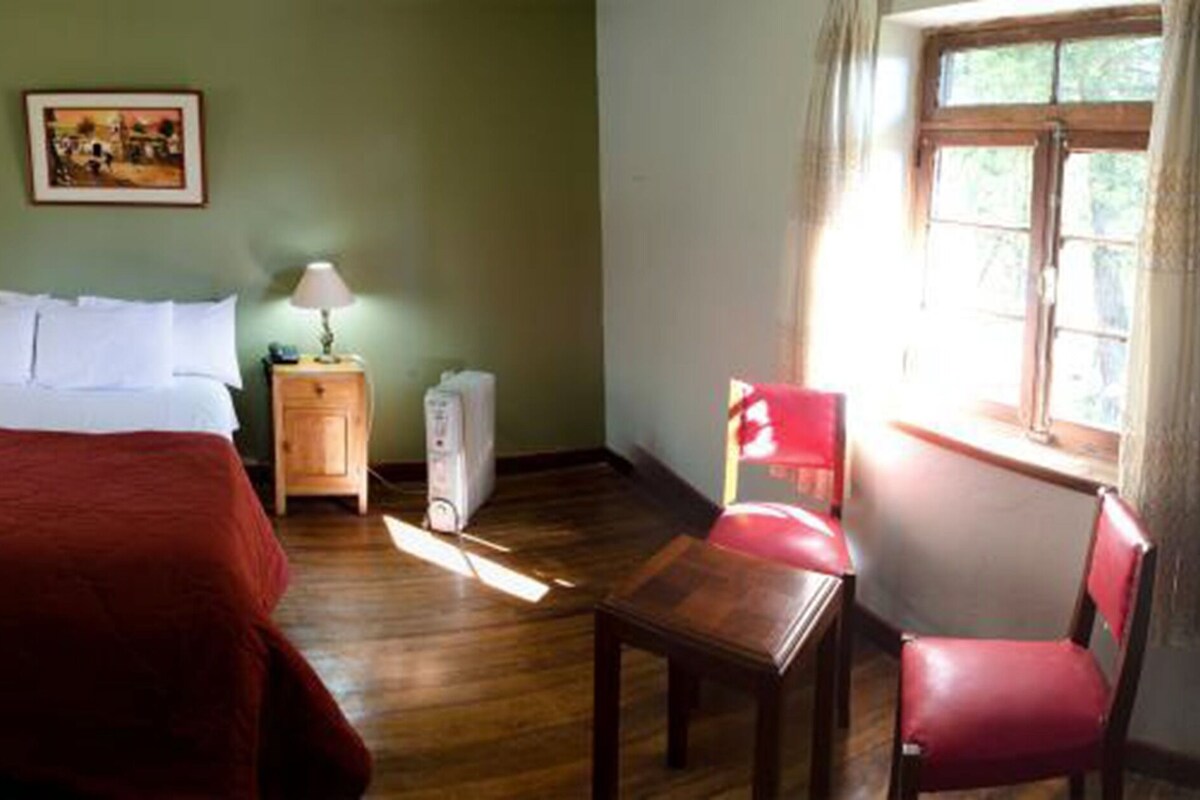A room with a bed, a nightstand, a chair, and a window.