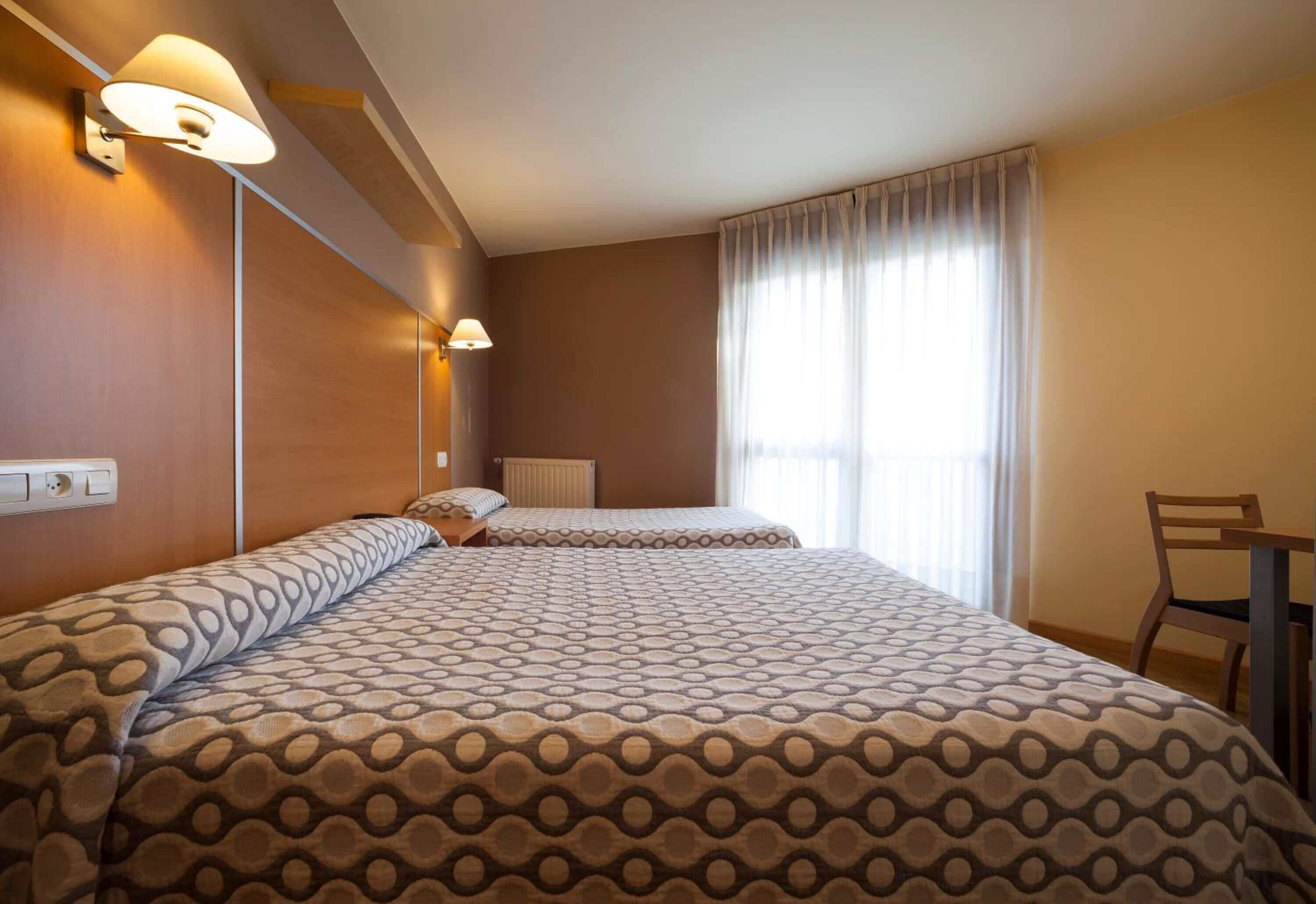 Habitación de hotel con dos camas, un escritorio y una silla.