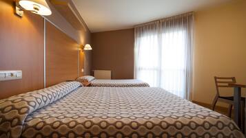 Habitación de hotel con dos camas, un escritorio y una silla.
