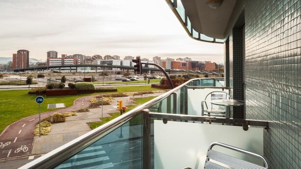 Un balcón con vistas a un paisaje urbano, una mesa y una silla.