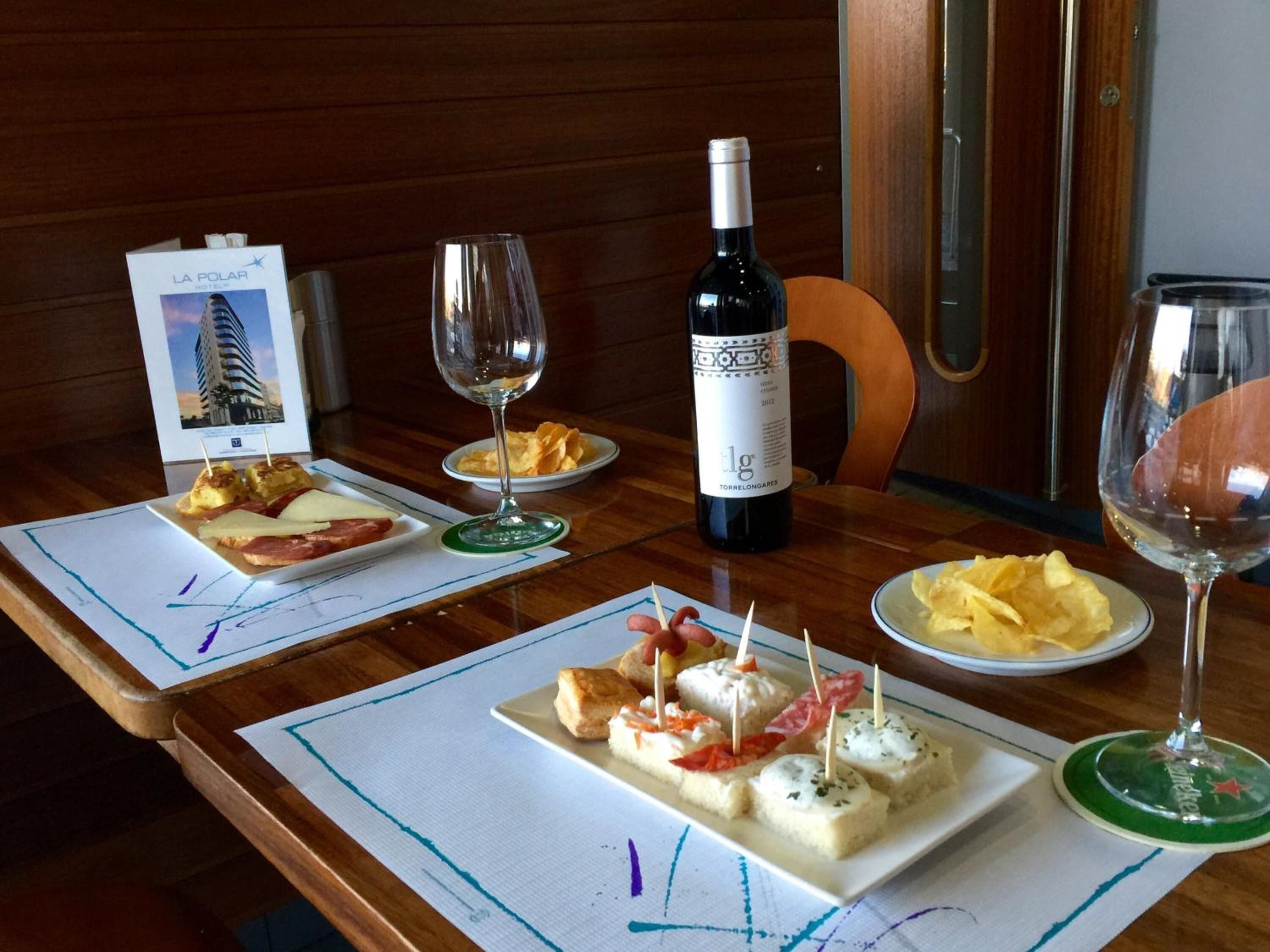 Una mesa de comedor con platos de aperitivos, una botella de vino y copas de vino.