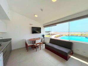 Uma sala de estar moderna com vista para a piscina, uma TV de tela plana e um espaço de jantar.