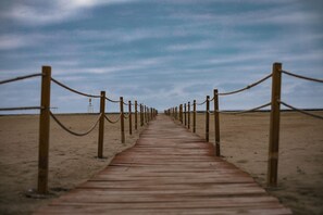Un sendero de madera que lleva a una playa bajo un cielo despejado.