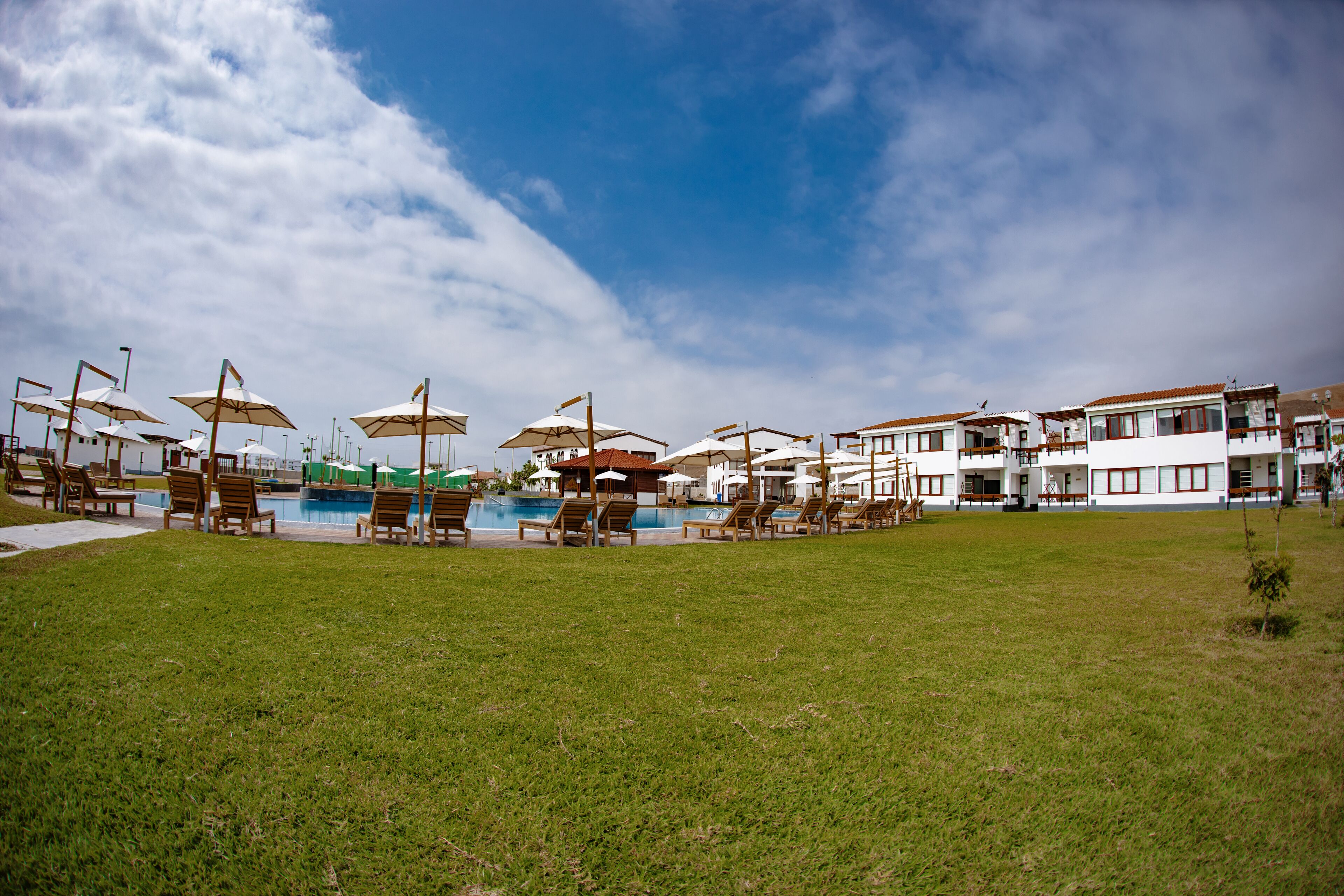 A pool area with lounge chairs and umbrellas, surrounded by buildings with balconies.