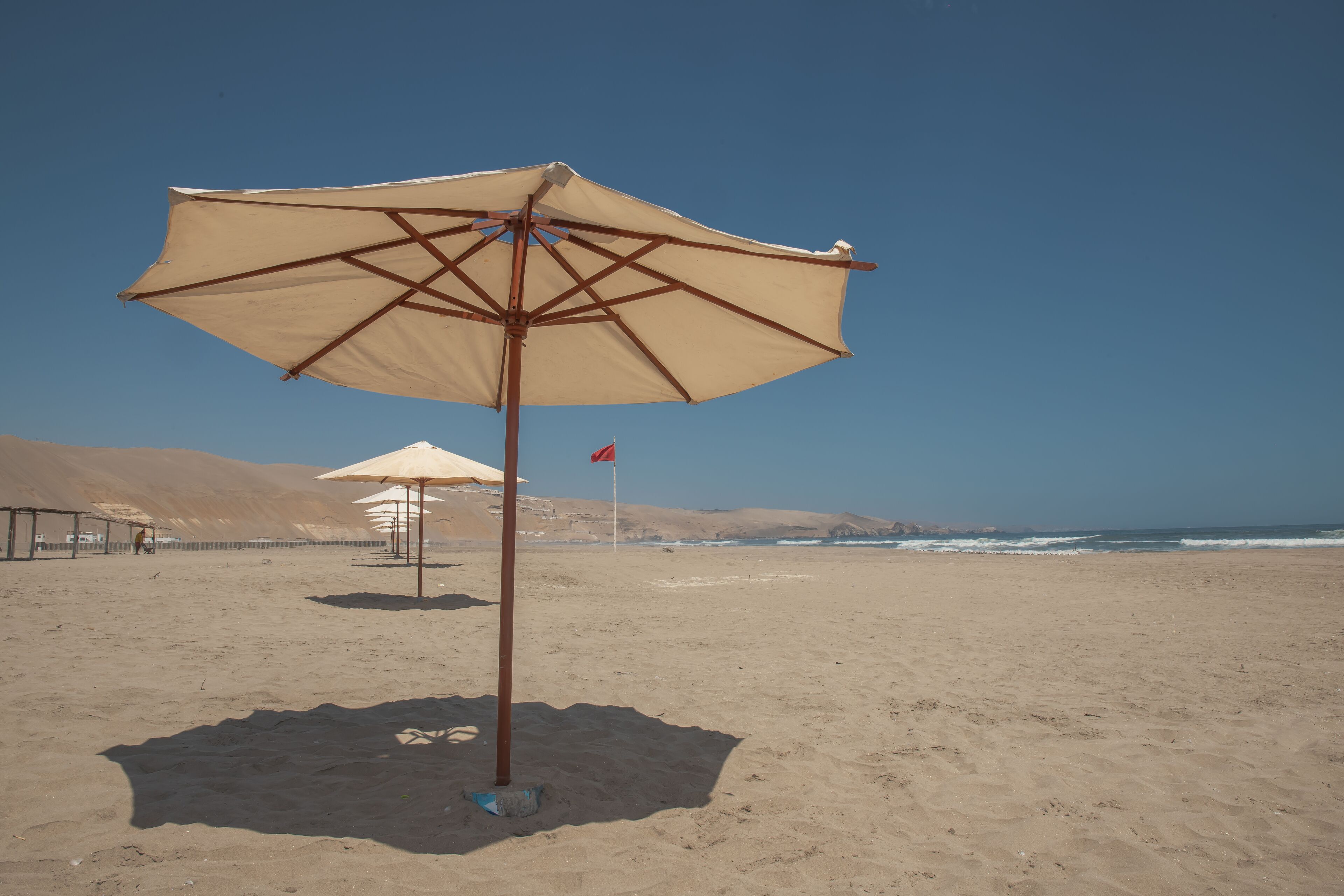 Uma praia com um guarda-sol grande e uma bandeira.