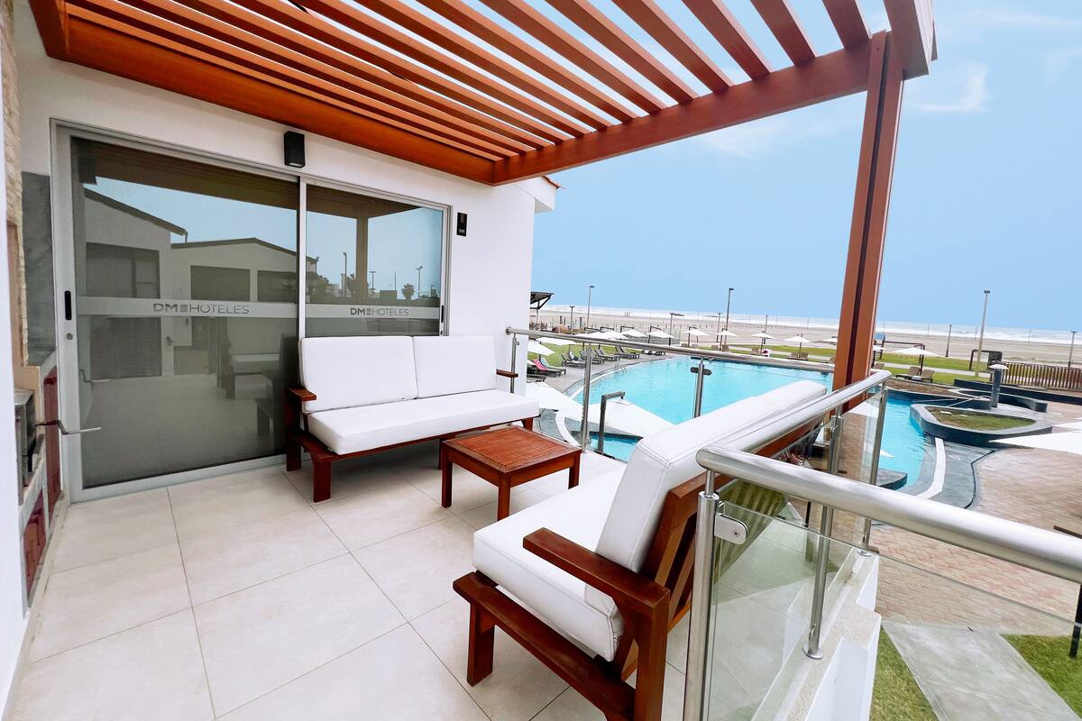 A balcony with a pool, white sofas, and a wooden pergola.