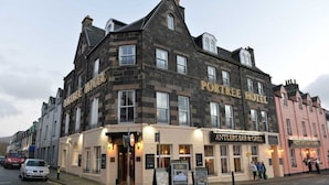 A multi-story building with the sign "Portree Hotel" and "Antlers Bar & Grill" on the ground floor. - The Portree Hotel (Portree)