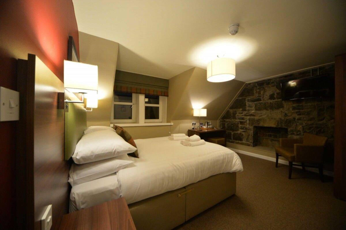Ein Schlafzimmer mit einem großen Bett, einem Steinkamin und einem an der Wand befestigten Fernseher.