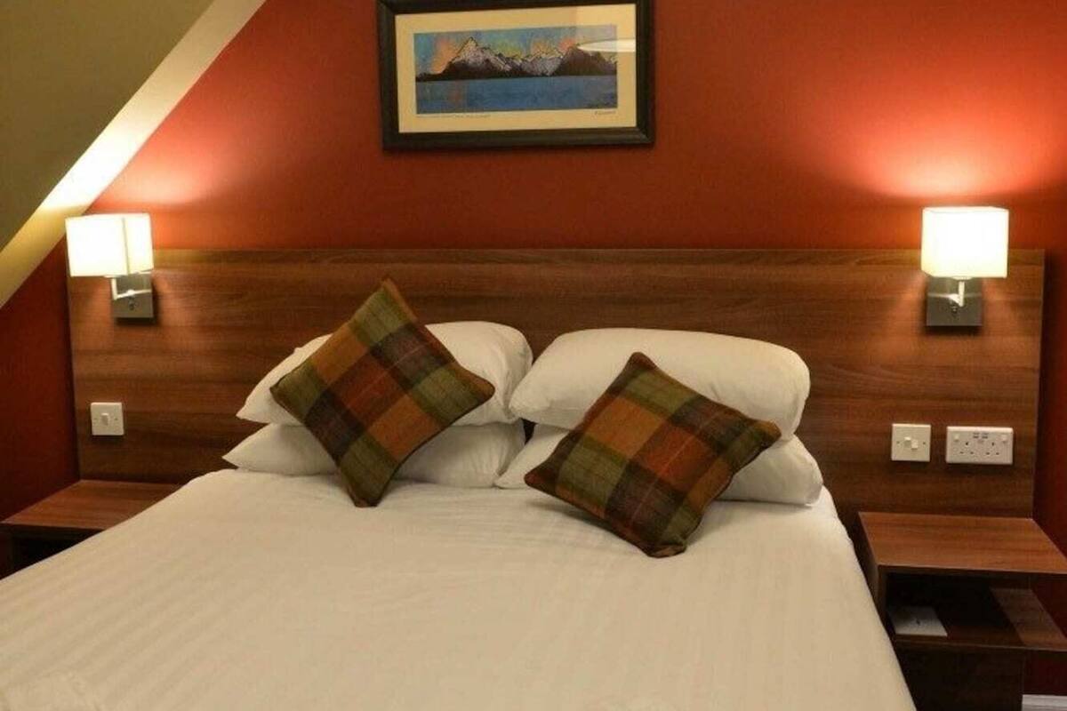 Ein Hotelzimmer mit einem großen Bett, zwei Nachttischlampen, einem Bild an der Wand und einer Deckenleuchte.