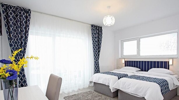 A modern hotel room with two beds, a dining area, and large windows. - Pension Mora Cluj Napoca (Cluj-Napoca)