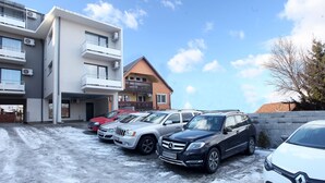A parking area with multiple cars, a building with balconies, and a clear sky. - Pension Mora Cluj Napoca (Cluj-Napoca)