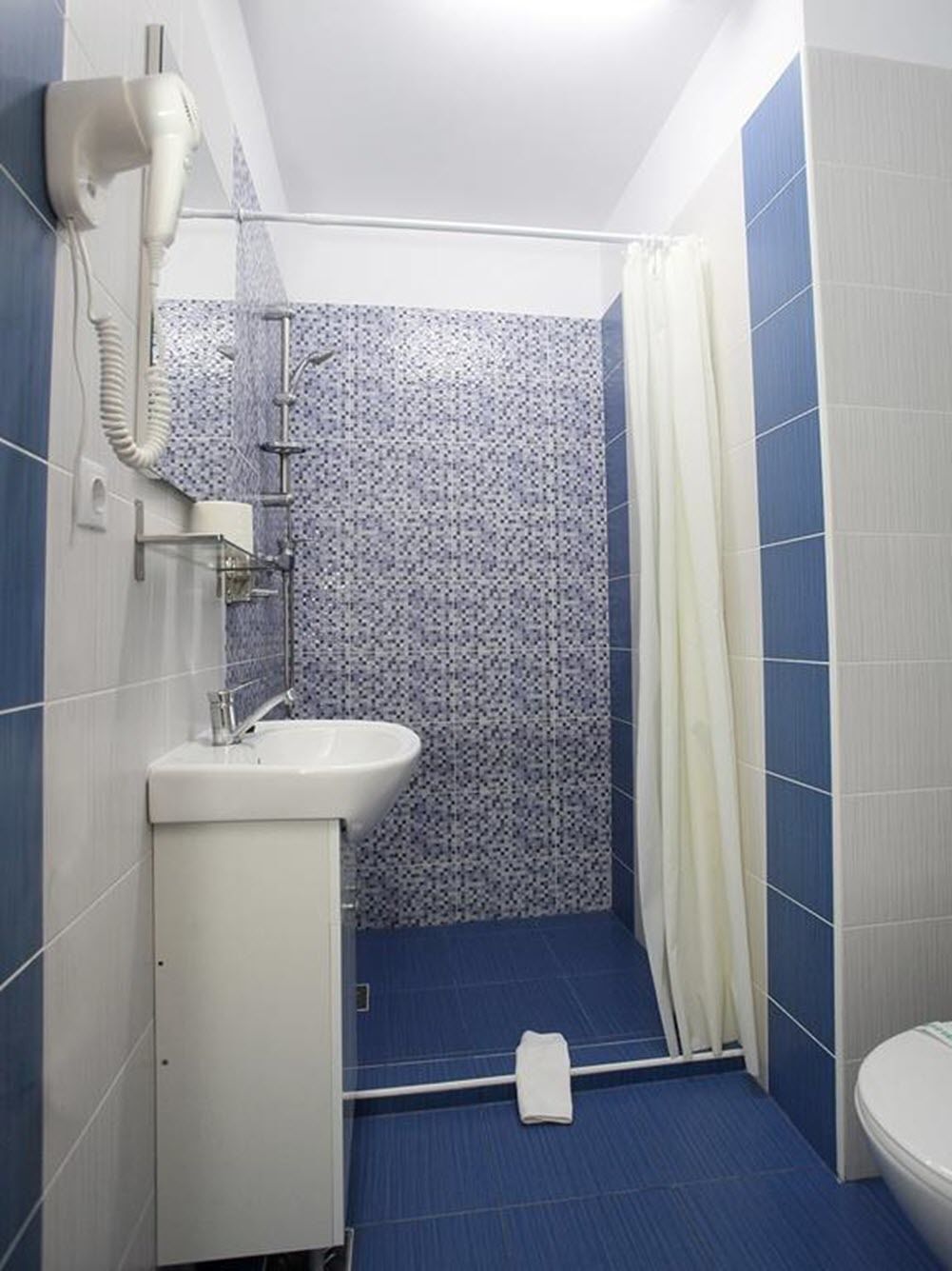A bathroom with a shower, a sink, and a toilet.