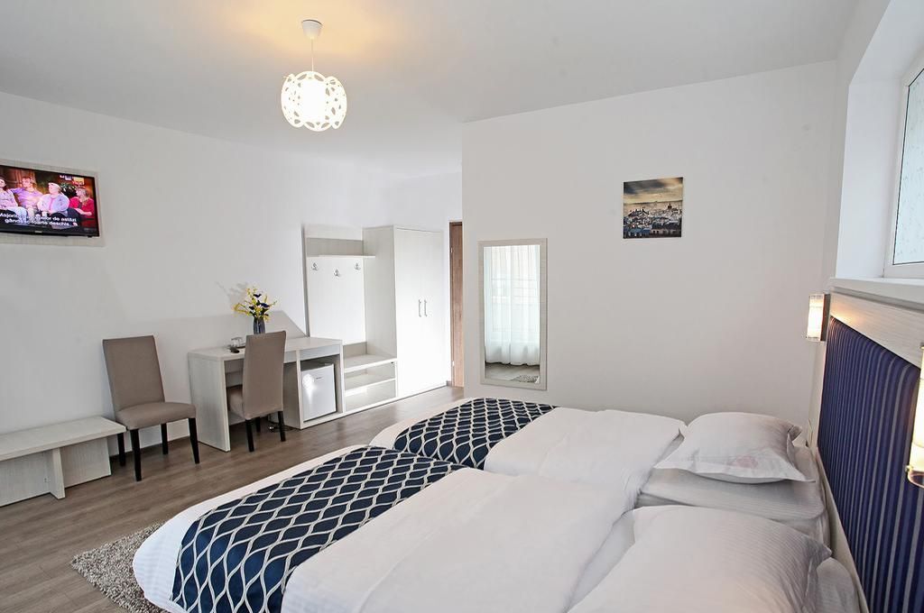 A hotel room with a bed, a desk, a chair, and a mirror.