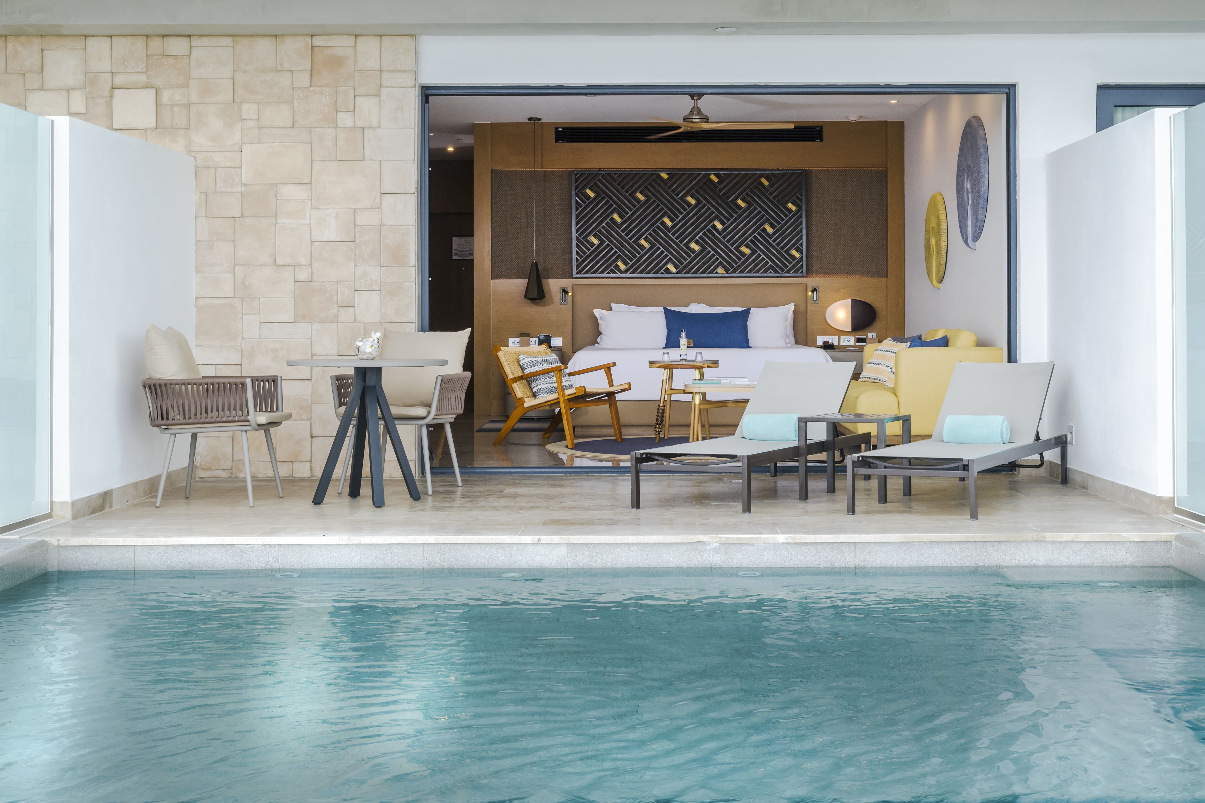 Habitación de hotel con piscina, cama, zona de comedor y cocina.