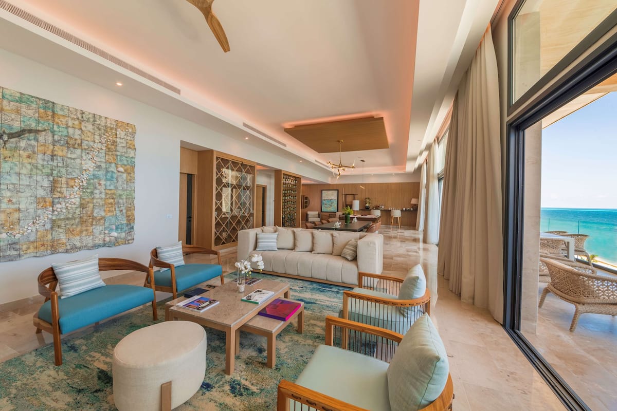 A spacious living area with a large window overlooking the ocean, a cozy seating arrangement, and a modern interior design.