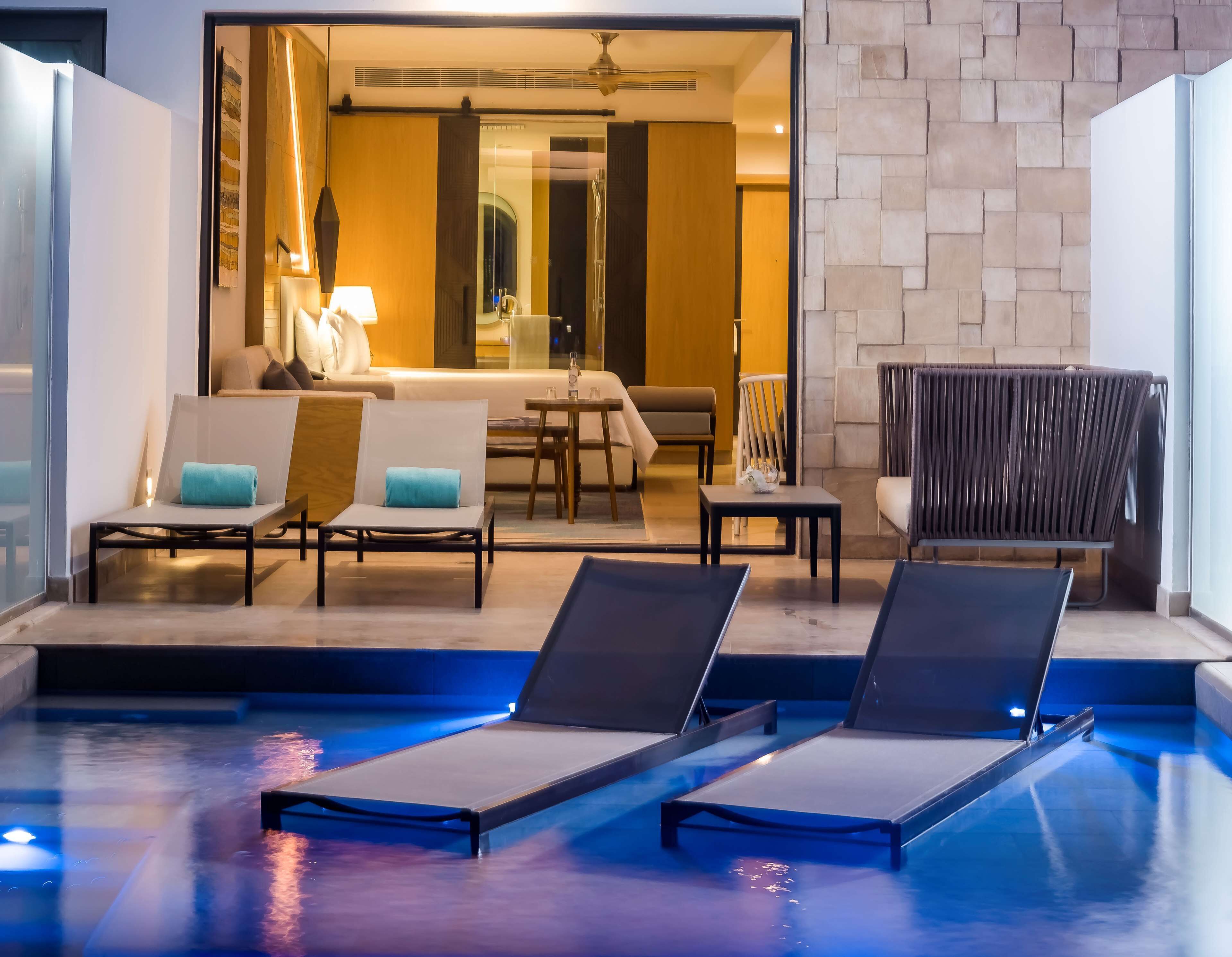 A modern indoor pool area with lounge chairs and a seating area.